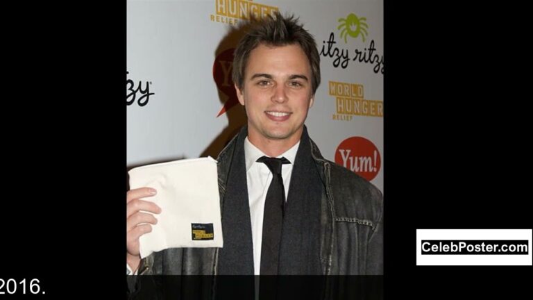 A person in a suit holding a napkin in front of a promotional backdrop with logos.