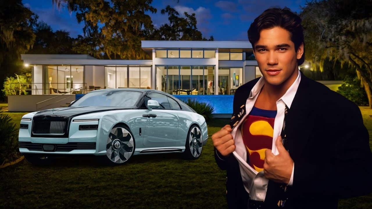 A man poses in front of a modern house at night, revealing a Superman shirt. A luxury car is parked on the lawn nearby.