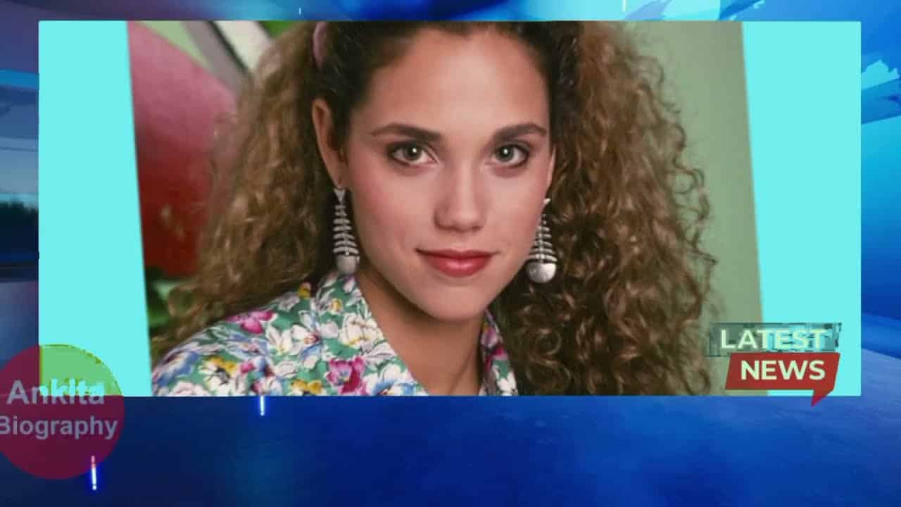 A woman with curly hair and earrings is shown in a framed portrait on a news graphic background.