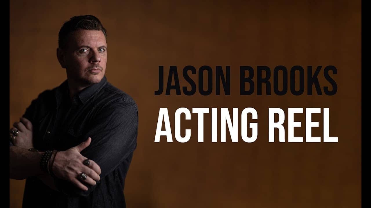 Man in a dark shirt stands with arms crossed, looking to the side. Text reads "Jason Brooks Acting Reel" against a brown background.