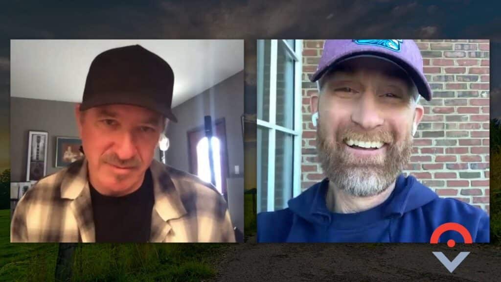 Two men in a video call, one wearing a black cap and plaid shirt indoors, the other wearing a purple cap and blue hoodie outside. Both are smiling against scenic backgrounds.