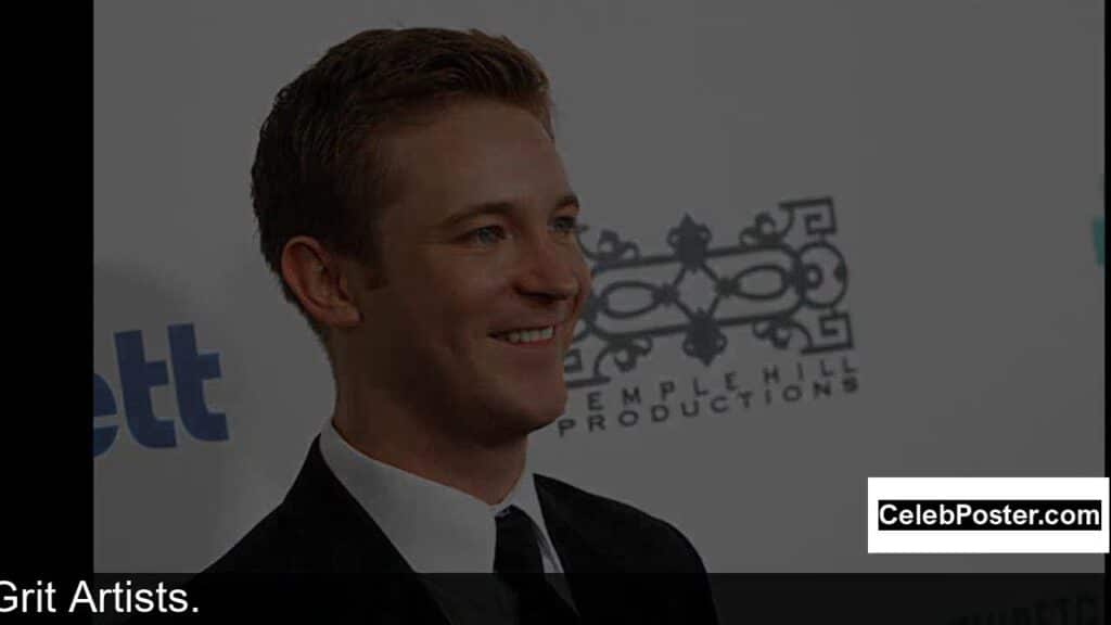 Man in a suit smiling at an event with a Temple Hill Productions backdrop.