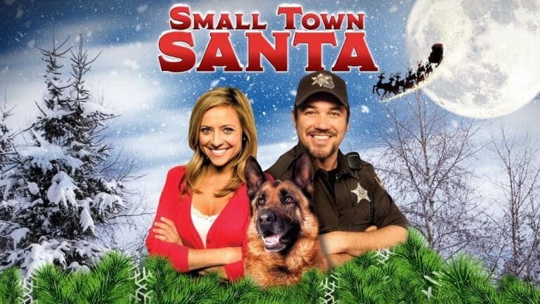 Two people and a dog stand in front of snowy trees under a night sky with a full moon and flying reindeer. "Small Town Santa" is written in red at the top.