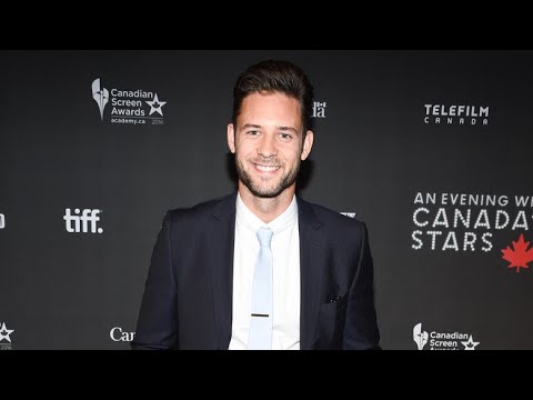 A man in a suit and tie stands smiling on a red carpet at an event with Canadian Screen Awards and Telefilm Canada logos in the background.