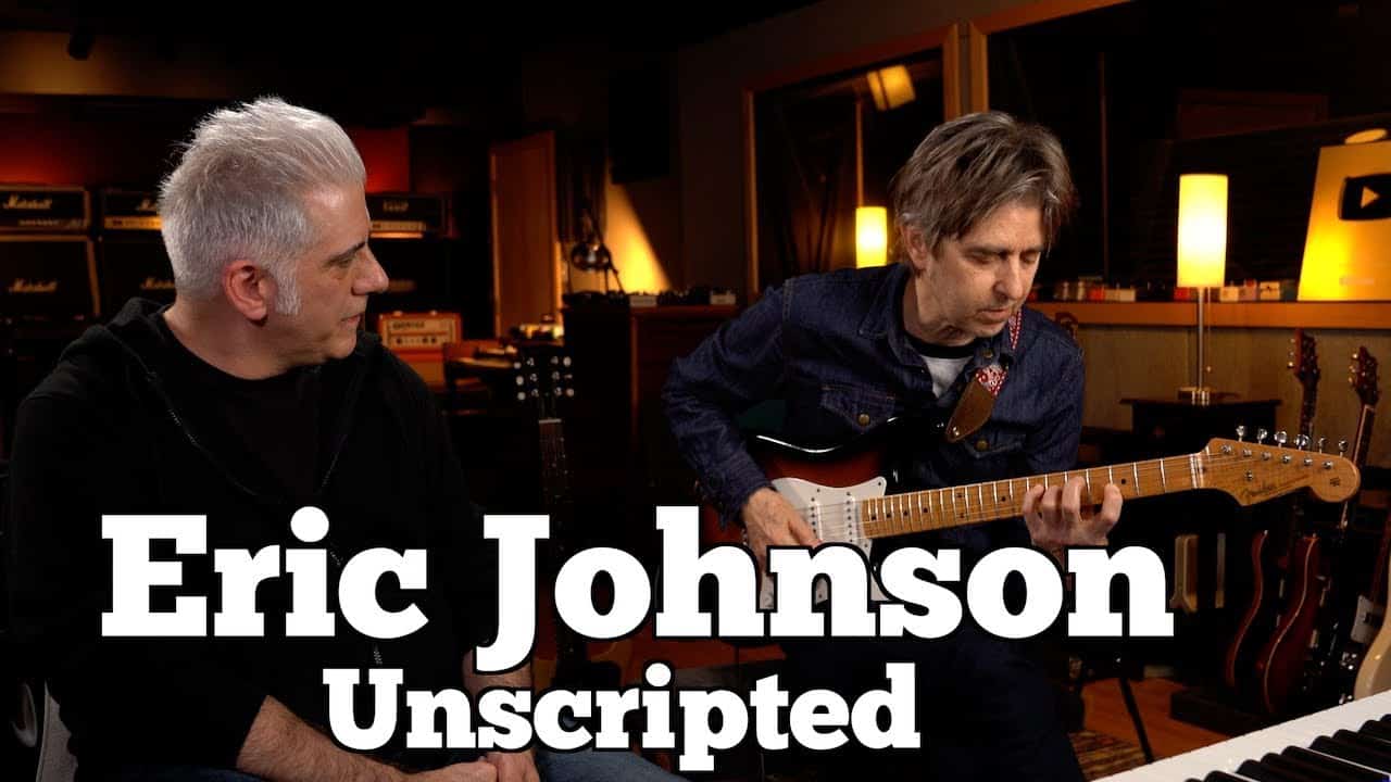 Two musicians in a studio, one playing an electric guitar while the other watches. Text on image reads "Eric Johnson Unscripted.