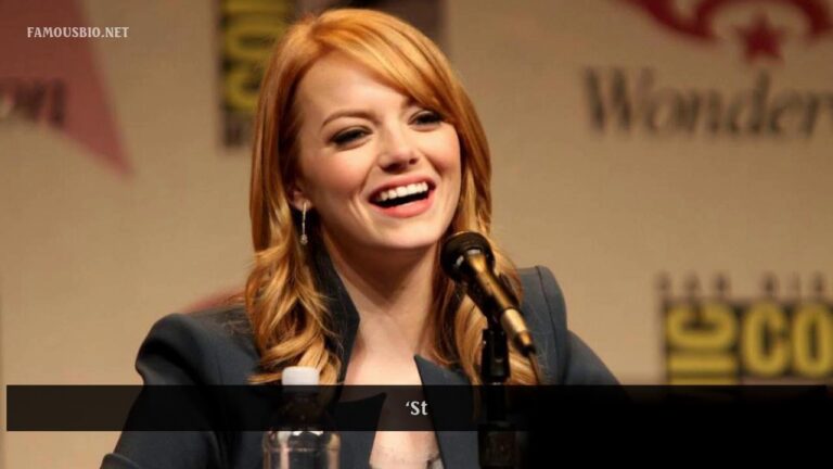 A person with red hair smiles and speaks into a microphone at a conference.